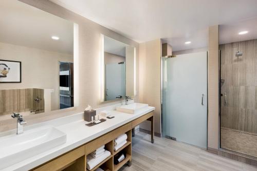 a bathroom with two sinks and a shower at Courtyard by Marriott Los Angeles Monterey Park in Monterey Park