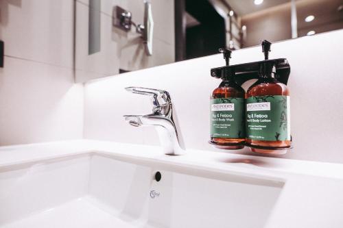 a bathroom sink with two bottles of alcohol on it at Crowne Plaza Belgrade by IHG in Belgrade