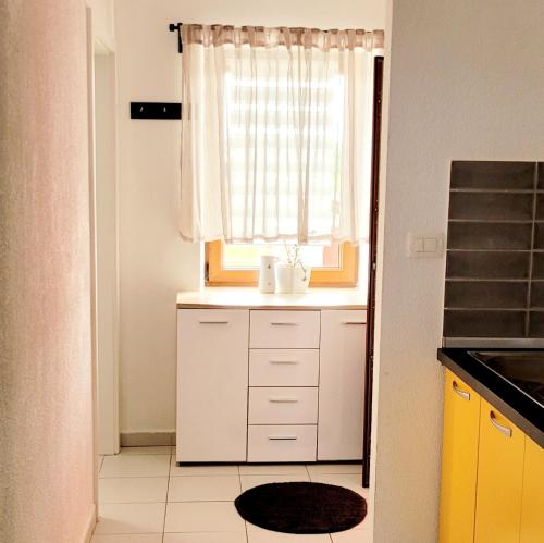 eine kleine Küche mit einem Fenster und einer weißen Theke in der Unterkunft Apartman Rocky in Petrovija