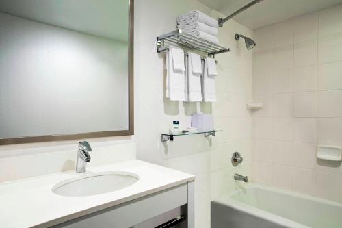 uma casa de banho com um lavatório, um espelho e uma banheira em The Chelsean New York em Nova York
