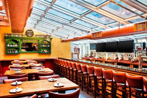 Un restaurante con mesas y sillas de madera y un bar. en The Chelsean New York, en Nueva York