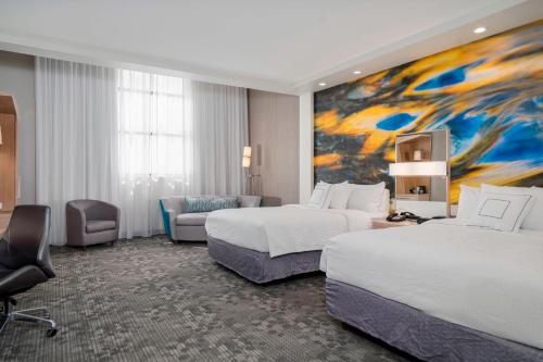 a hotel room with two beds and a painting at Courtyard by Marriott Niagara Falls, USA in Niagara Falls