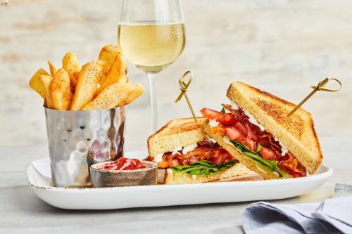 a sandwich and french fries on a plate with a glass of wine at Courtyard by Marriott Albion in Albion