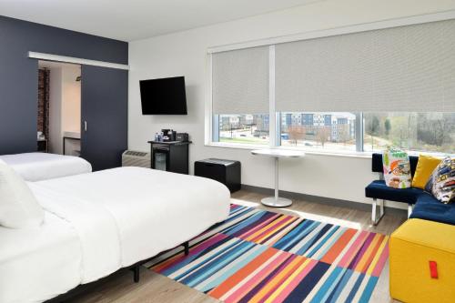 um quarto com uma cama branca e um tapete colorido em Aloft Charlotte Airport em Charlotte