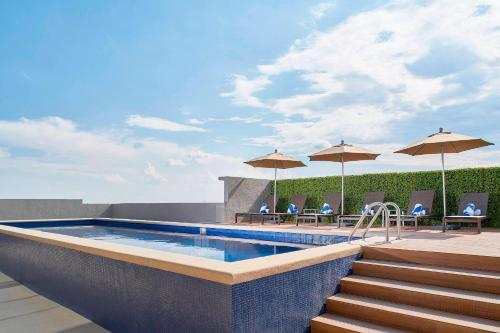 - une piscine avec des chaises et des parasols dans un bâtiment dans l'établissement Fairfield Inn & Suites by Marriott Aguascalientes, à Aguascalientes