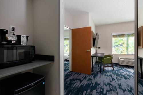 a hotel room with a door open to a room with a table at Fairfield Inn & Suites by Marriott Atlanta Stonecrest in Lithonia