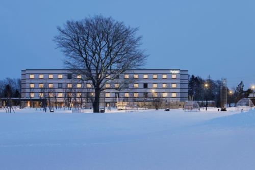 un bâtiment avec un arbre dans un champ de neige dans l'établissement Fairfield by Marriott Hokkaido Eniwa, à Eniwa