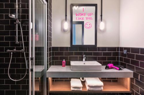 ein Bad mit einem Waschbecken und einer Dusche in der Unterkunft Moxy Duesseldorf South in Düsseldorf