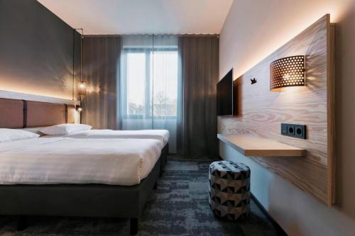 a hotel room with two beds and a desk at Moxy Duesseldorf South in Düsseldorf