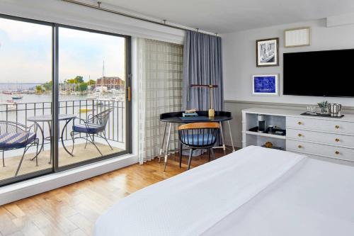 a bedroom with a bed and a balcony with a table at Annapolis Waterfront Hotel, Autograph Collection in Annapolis