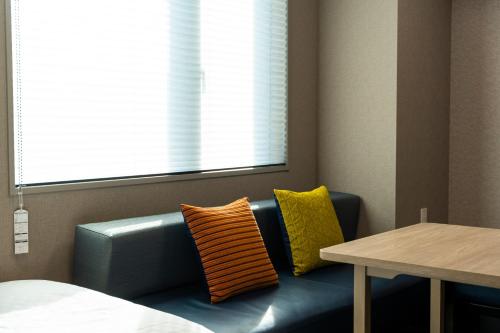 a blue couch sitting under a window next to a table at KOKO HOTEL Residence Asakusa Kappabashi in Tokyo