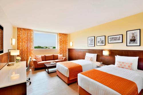 une chambre d'hôtel avec deux lits et un canapé dans l'établissement Fairfield by Marriott Amritsar, à Amritsar
