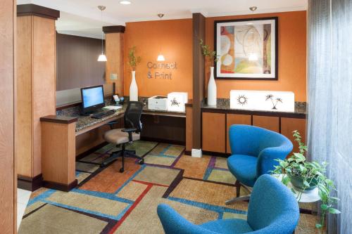Fairfield Inn & Suites Jacksonville Butler Boulevard في جاكسونفيل: مكتب الأسنان مع الكراسي الزرقاء ومكتب وكمبيوتر