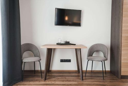 a table with two chairs and a tv on a wall at Guesthouse Karnatsch in Parcines