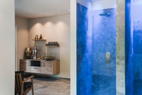 a bathroom with a blue shower and a kitchen at Guesthouse Karnatsch in Parcines