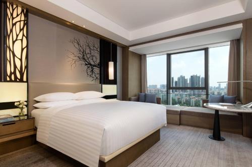 a bedroom with a large bed and a large window at Courtyard by Marriott Changsha South in Changsha