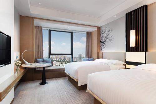長沙市にあるCourtyard by Marriott Changsha Southのベッド2台とテレビが備わるホテルルームです。
