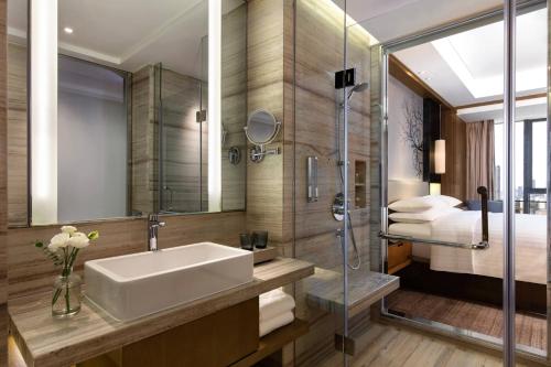 a bathroom with a sink and a shower and a bed at Courtyard by Marriott Changsha South in Changsha