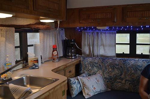 a kitchen with a sink and a couch in a caravan at The blue rooster 