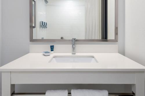 lavabo blanco en el baño con espejo en Four Points Huntsville Airport, en Madison