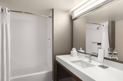 een badkamer met een wastafel, een bad en een spiegel bij Courtyard by Marriott Seattle Northgate in Seattle