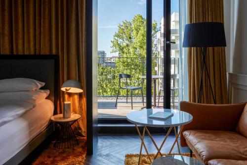 a hotel room with a bed and a view of a balcony at Roomers Munich, Autograph Collection in Munich