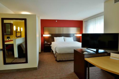 a hotel room with a bed and a mirror at Residence Inn by Marriott Omaha Aksarben Village in Omaha