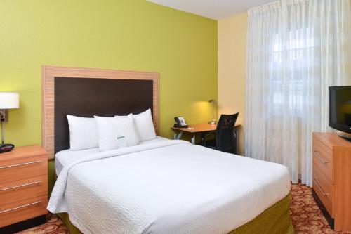 um quarto de hotel com uma cama grande e uma televisão em TownePlace Suites Miami West Doral Area em Miami
