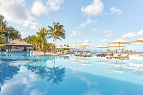 - une piscine avec des chaises et des parasols sur la plage dans l'établissement InterContinental Mauritius Resort Balaclava Fort, an IHG Hotel, à Balaclava