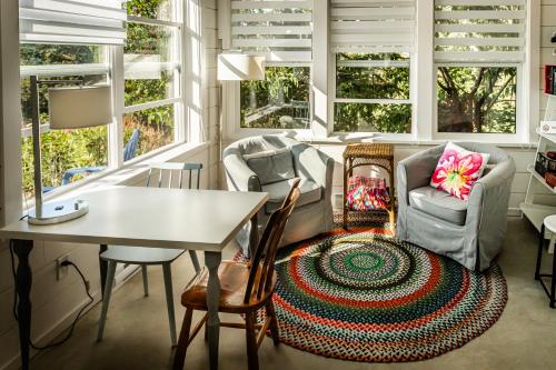 a living room with a table and chairs and windows at Belle Maison Auprès De La Mer in Sidney