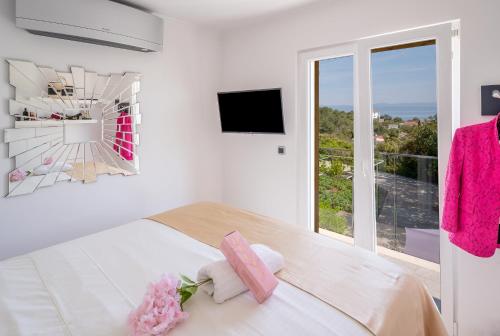 a white bedroom with a bed and a large window at Uniquely designed Villa Ivana with outdoor Jacuzzi nearby the pebble Banje beach at the Island of Solta in Rogač