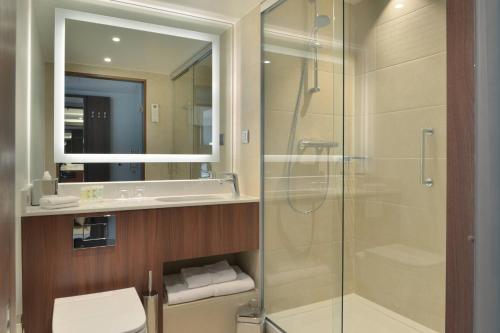 a bathroom with a shower and a toilet and a sink at Courtyard by Marriott Brussels EU in Brussels