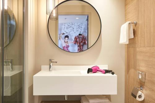 a bathroom with a white sink and a mirror at Moxy Patra Marina in Patra