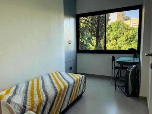 1 dormitorio con cama, escritorio y ventana en 2-bd apartment at the heart of the Carmel en Haifa