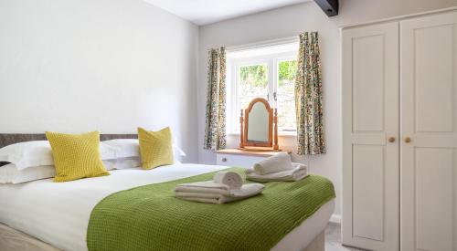 a bedroom with a bed with towels on a green blanket at Ullswater at the Graythwaite Estate in Ambleside