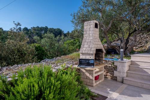 a brick oven in a garden with trees in the background at Uniquely designed Villa Ivana with outdoor Jacuzzi nearby the pebble Banje beach at the Island of Solta in Rogač