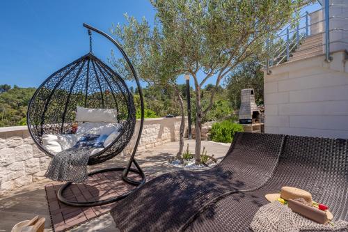 a metal swing sitting on a patio at Uniquely designed Villa Ivana with outdoor Jacuzzi nearby the pebble Banje beach at the Island of Solta in Rogač