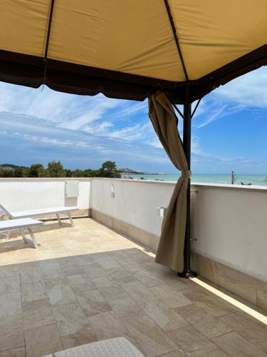 a large umbrella on a balcony with the ocean in the background at Villa Latino in Vieste