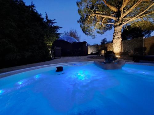 un homme dans un jacuzzi dans une cour la nuit dans l'établissement Chambre bulle avec spa au cœur du val de Loire, à Cheillé