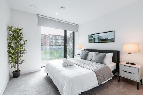 1 dormitorio con cama blanca y ventana grande en Khayat Homes - The Canex - One Bed, en Londres