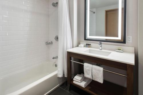een badkamer met een wastafel, een bad en een spiegel bij Four Points by Sheraton Albany in Albany