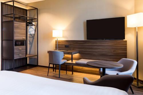a hotel room with a bed and a desk and a tv at AC Hotel by Marriott Mainz in Mainz