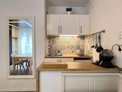 une cuisine avec des placards blancs et une table avec une salle à manger dans l'établissement Pied-à-terre au centre de Cauterets. 4 personnes., à Cauterets