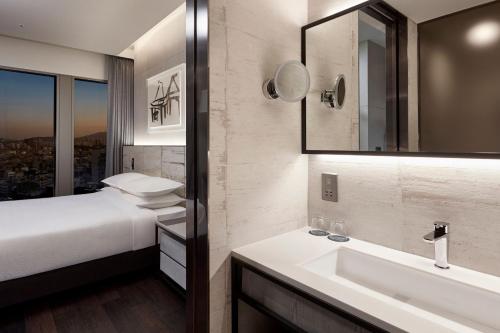 y baño con cama, lavabo y espejo. en Four Points by Sheraton Seoul Gangnam en Seúl