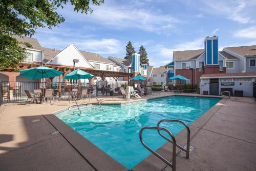 a swimming pool with chairs and umbrellas at a hotel at Residence Inn by Marriott Sacramento Airport Natomas in Sacramento