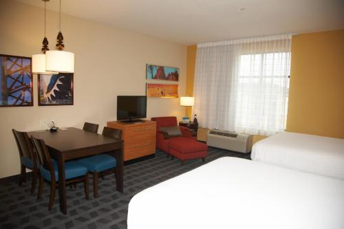 a hotel room with a desk and a bed and a bedroom at TownePlace Suites by Marriott Hobbs in Hobbs