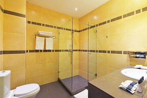 a bathroom with a shower and a toilet and a sink at Protea Hotel by Marriott Kampala in Kampala