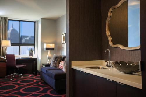 ボストンにあるCourtyard by Marriott Boston Downtownのシンクと青いソファが備わるホテルルームです。