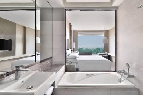 a bathroom with a tub and a bed and a mirror at Kathmandu Marriott Hotel in Kathmandu