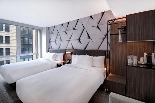 two beds in a hotel room with a large window at SpringHill Suites by Marriott New York Midtown Manhattan/Park Ave in New York